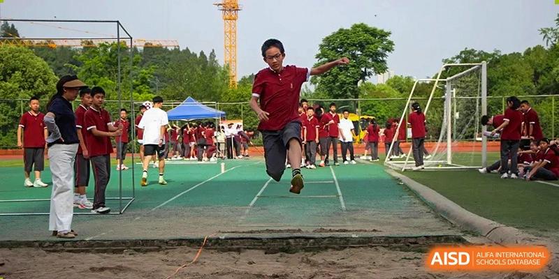 A student performing a long jump into a sand pit during a track and field competition at Yichang Tianwen International School.