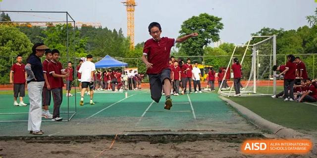 A student performing a long jump into a sand pit during a track and field competition at Yichang Tianwen International School.