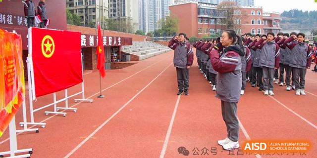 A school official or teacher standing on the red running track observing a student formation or ceremony at Yichang Tianwen International School.