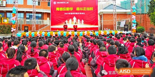 A high angle view of a large crowd of students in red jackets sitting in an assembly area outdoors at Yichang Tianwen International School.