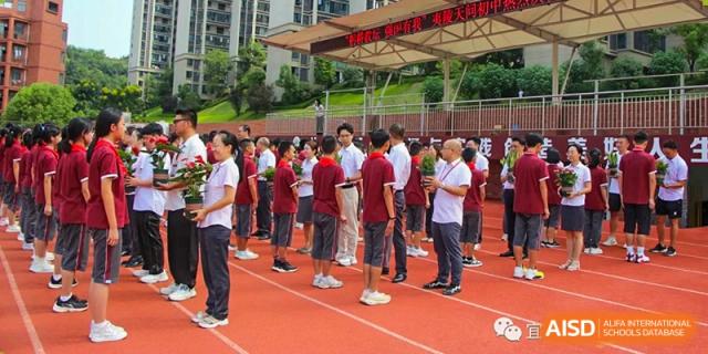 A group of students in red and white uniforms standing in a line on a red running track during a physical education class or event at Yichang Tianwen International School.