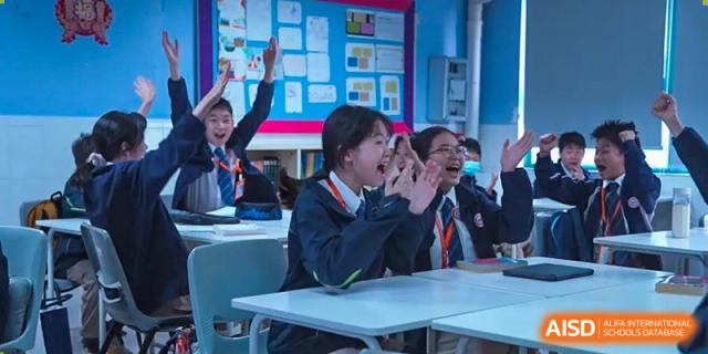 Students from Shenzhen Oasis International School smiling and laughing at their desks during class.