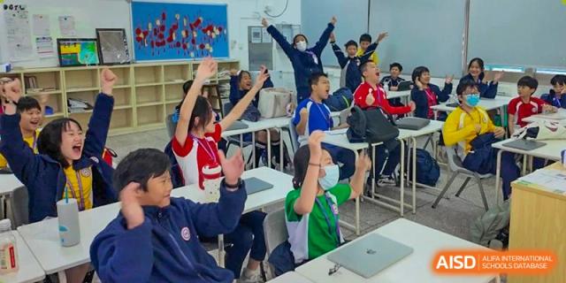 Students from Shenzhen Oasis International School enthusiastically raising their hands during a classroom lesson.