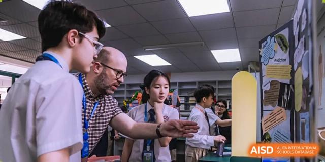A teacher from Shenzhen Oasis International School helps a student with a book in the school library.