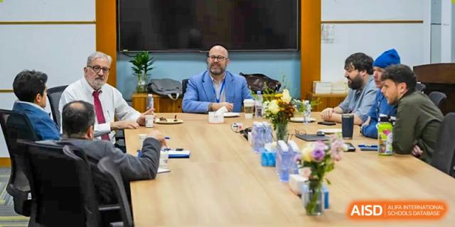A teacher and students from Shenzhen Oasis International School sit at a conference table.