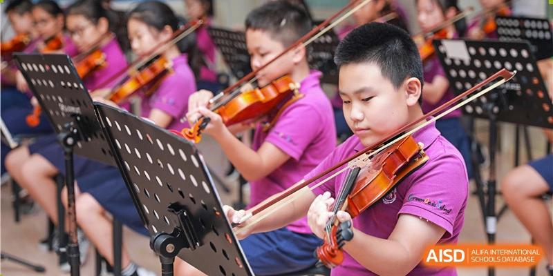 A male student from Shenzhen Oasis International School plays the violin as part of a school orchestra.