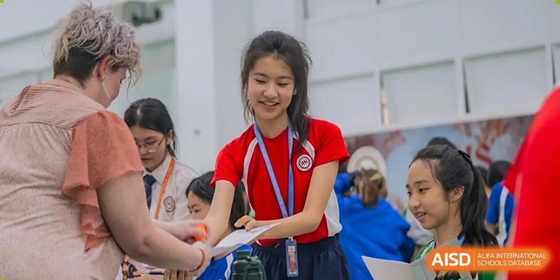 A female student from Shenzhen Oasis International School hands out a flyer at a school event.