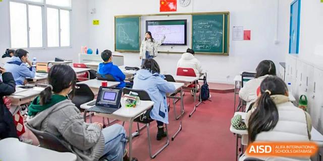 A teacher from World Leading Schools Association leading a class discussion while writing on a whiteboard.
