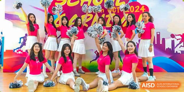 World Leading Schools Association cheerleading squad performing a routine with pom-poms in a gymnasium.