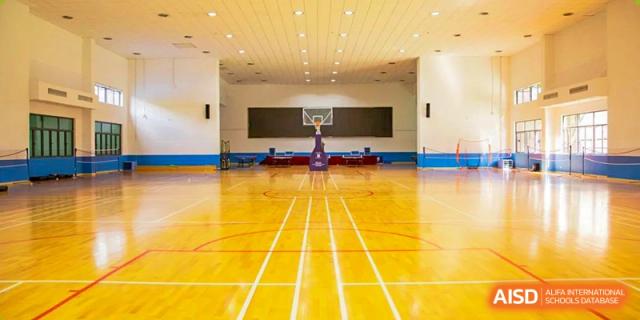 An empty, well-lit indoor gymnasium and basketball court at the World Leading Schools Association campus.