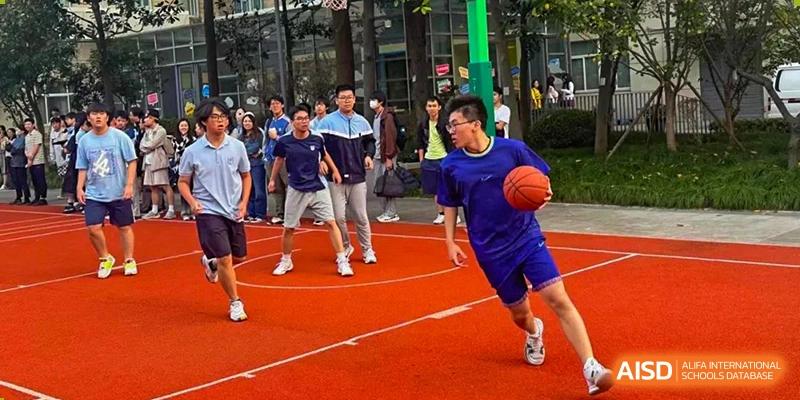 A student from World Leading Schools Association dribbling a basketball during an outdoor game on a red court.