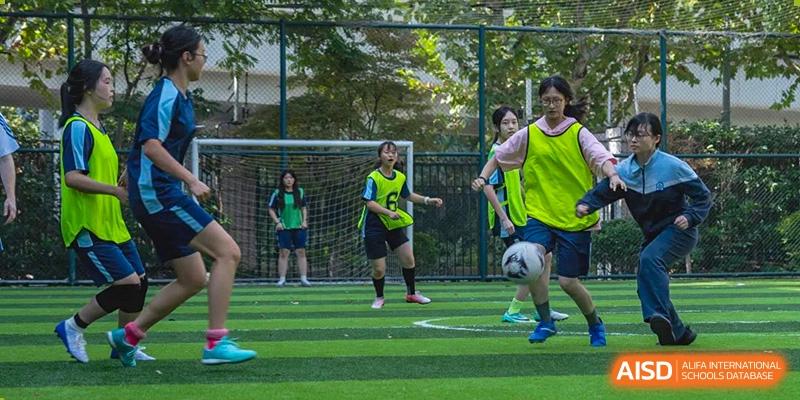 Students from World Leading Schools Association playing soccer on a green turf field.