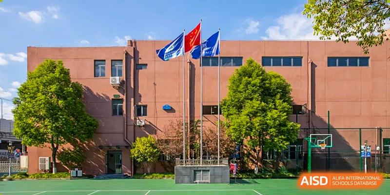 The exterior of the World Leading Schools Association building with flagpoles displaying red and blue flags.