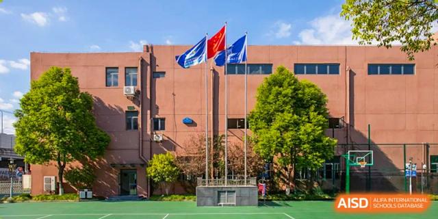 The exterior of the World Leading Schools Association building with flagpoles displaying red and blue flags.
