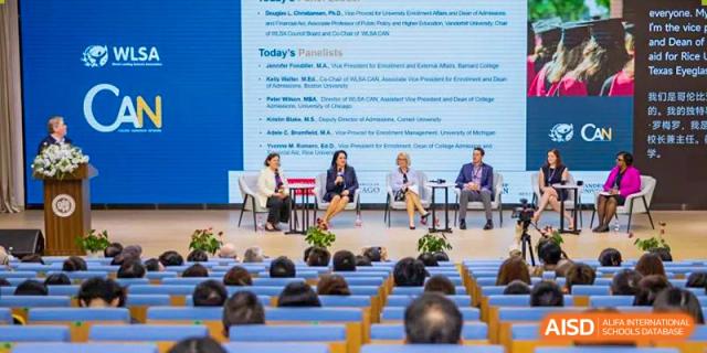 A panel discussion with speakers seated on a stage, viewed from the audience at a World Leading Schools Association event.