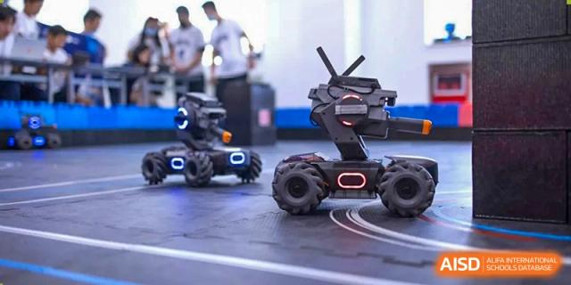 Harrow International School Shenzhen robotics students operating two black robots on a track.