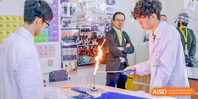 Harrow International School Shenzhen a teacher or scientist demonstrating a science experiment with a flame to students.
