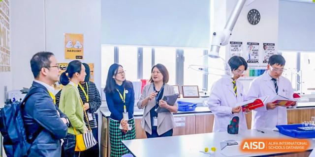 Harrow International School Shenzhen students and a teacher having a conversation in a modern laboratory.