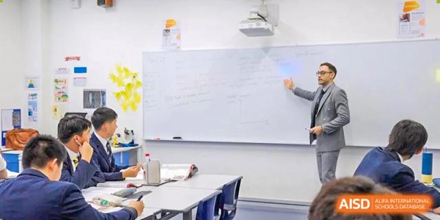 Harrow International School Shenzhen students gathered around a whiteboard with a teacher, writing notes in a classroom.