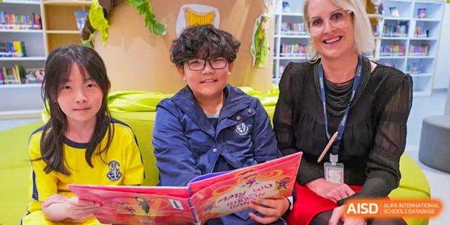 Harrow International School Shenzhen student wearing glasses and reading a book in a school library.
