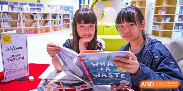 Harrow International School Shenzhen students reading books in a library, one holding a book titled "What a Waste".