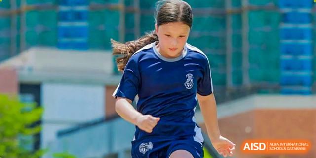 Harrow International School Shenzhen student in a blue and white sports uniform running during a game.