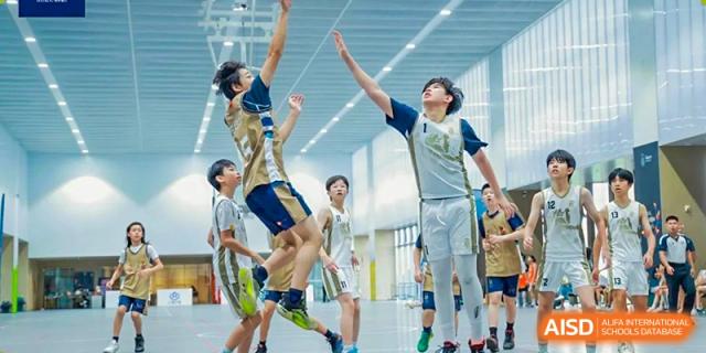 Harrow International School Shenzhen students playing volleyball one student leaps to spike the ball while another jumps to block.