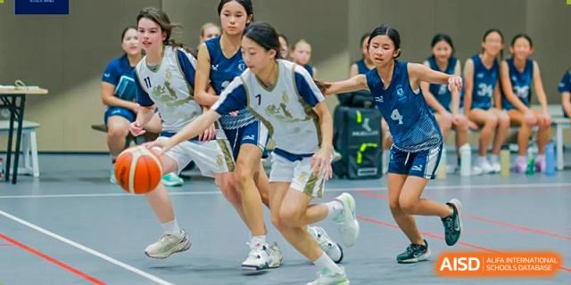 Harrow International School Shenzhen students playing a game of basketball indoors.