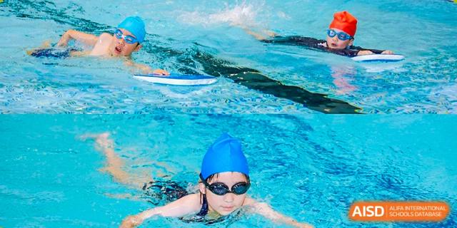 Harrow International School Shenzhen student in a blue swim cap and goggles, swimming laps in a pool.