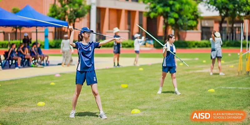 Harrow International School Shenzhen student practicing throwing a javelin in a grassy field during a sports class.