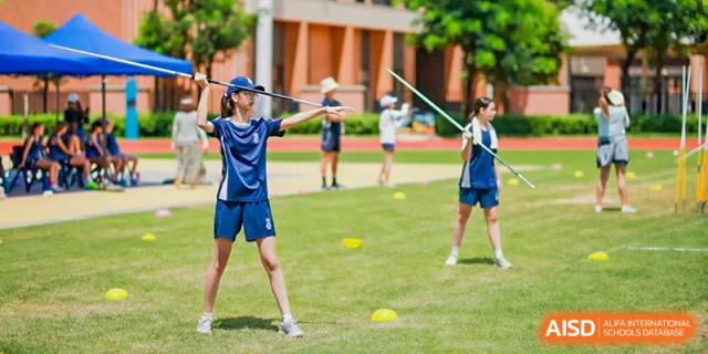 Harrow International School Shenzhen student practicing throwing a javelin in a grassy field during a sports class.