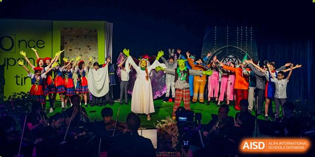 Harrow International School Shenzhen students performing on a stage in a theatrical production with colorful costumes.