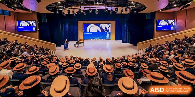 Harrow International School Shenzhen students seated in an auditorium, watching a performance on a stage with a grand piano.