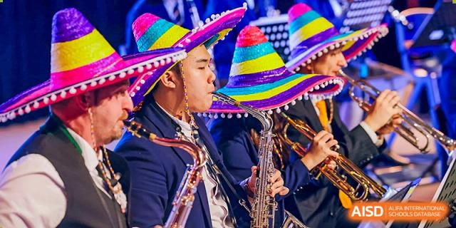 Harrow International School Shenzhen students performing with musical instruments and wearing festive, colorful sombreros.