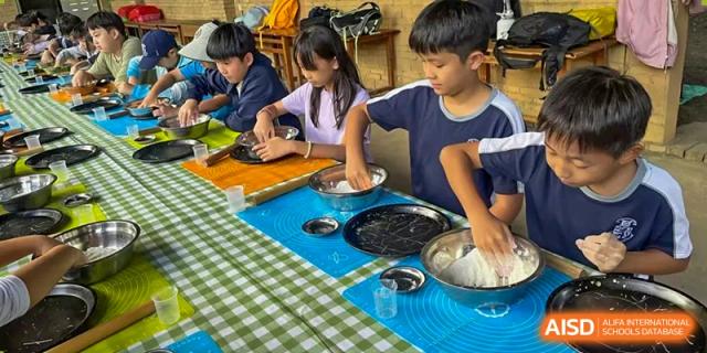 Harrow International School Shenzhen students working on a baking or cooking project, kneading dough at a table.