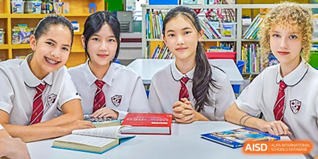 International School of Nanshan Shenzhen female students in school uniforms sitting at a desk and smiling.