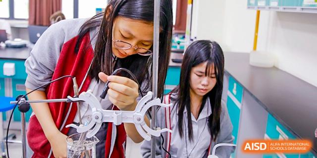 International School of Nanshan Shenzhen two female students focused on a project, with one wearing glasses.