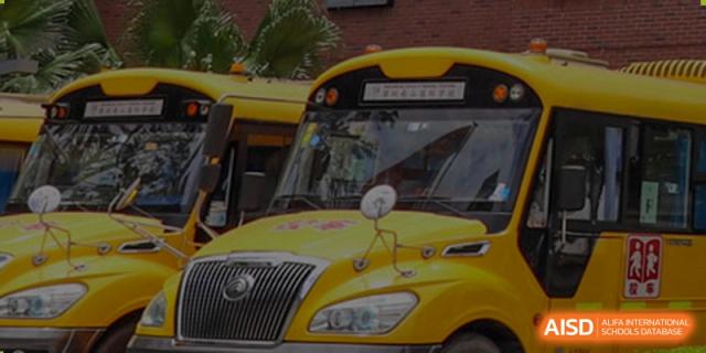 International School of Nanshan Shenzhen school bus with the school's logo is parked in front of the campus.