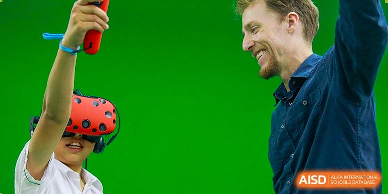 International School of Nanshan Shenzhen a smiling man's face from the side, possibly a teacher or coach, against a green background.