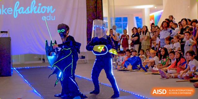 International School of Nanshan Shenzhen young students in blue light-up costumes performing on a stage.