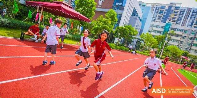 International School of Nanshan Shenzhen female student running on a red track during a sports activity.
