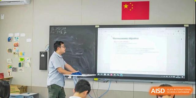 A teacher presenting a lesson on a large interactive whiteboard to a student in a Shenzhen Yunding School classroom.