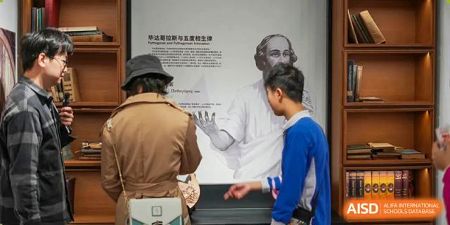 Shenzhen Yunding School students viewing a display about a historical or scientific figure in a museum-like setting.