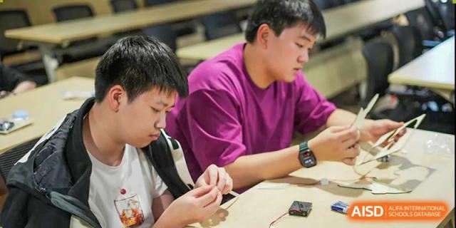 Shenzhen Yunding School students collaboratively working on a hands-on electronic or technical project at a table.
