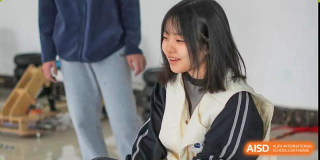 A smiling female student from Shenzhen Yunding School looks off-camera, participating in an activity or discussion.