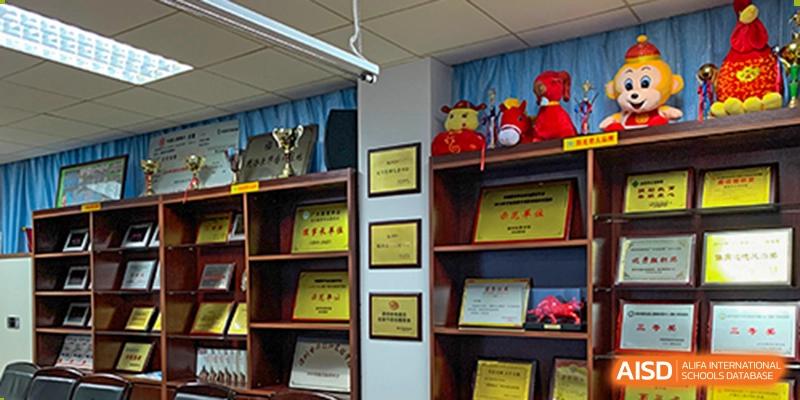 A wall display at Shenzhen Yunding School featuring various framed awards, certificates, and trophies.