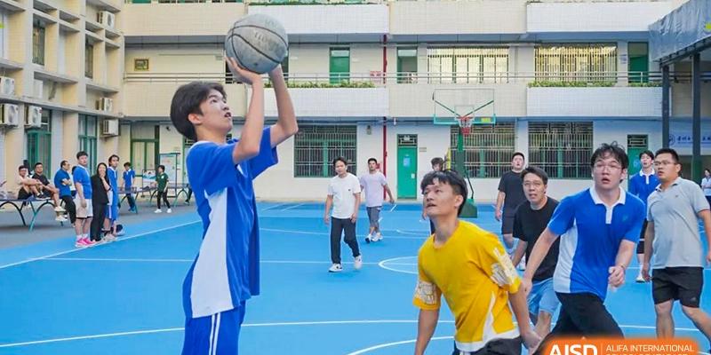 Shenzhen Yunding School students playing basketball outdoors on a blue court with school buildings in the background.