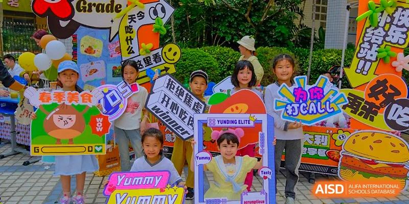 Young students from Shenzhen Yunding School holding promotional signs or banners at an outdoor event.
