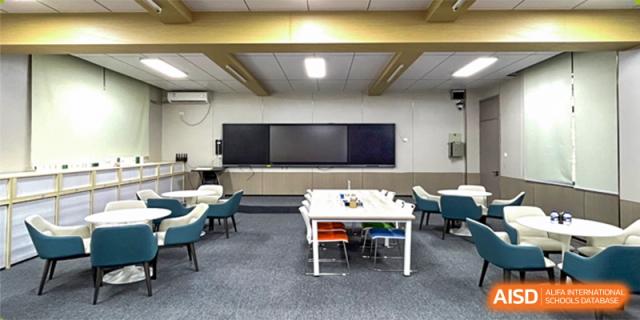 A modern collaborative classroom or lab at Shenzhen Yunding School featuring large interactive screens and a central table.