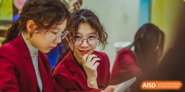 A teacher from Beijing Concord College of Sino-Canada is smiling at a student in a classroom setting.